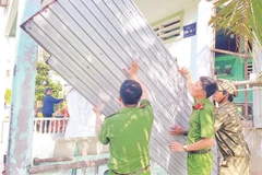 Lực lượng tình nguyện Công an tỉnh Cà Mau giúp người dân tháo dỡ nhà tạm, nhà dột nát.