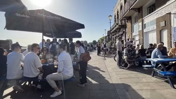 Người dân thưởng thức đồ uống tại các pub ven sông Thames trong ngày nắng nóng. (Ảnh: Hương Giang/TTXVN)