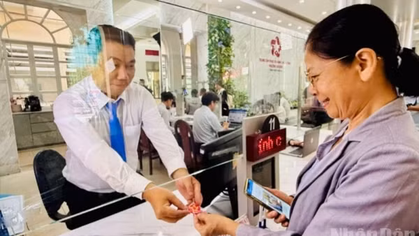 Bà Phùng Thị Nguyệt được cán bộ phường Sài Gòn tặng món quà lưu niệm nhỏ trong ngày đầu tiên vận hành mô hình chính quyền địa phương 2 cấp. (Ảnh: VƯƠNG LÊ)