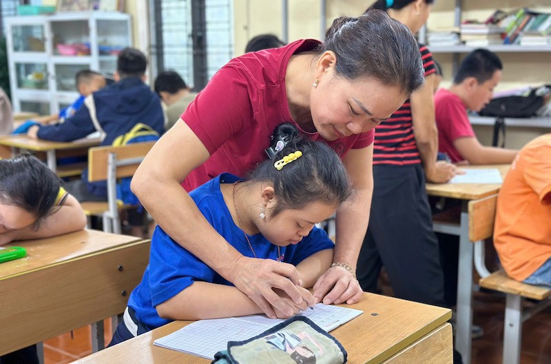 Cô Lê Thị Hòa đang hướng dẫn học sinh viết chữ.