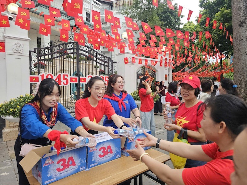 Các bạn tình nguyện viên phát nước cho người dân đi xem sơ duyệt diễu binh, diễu hành tại Hà Nội. (Ảnh: THẾ ĐẠI)