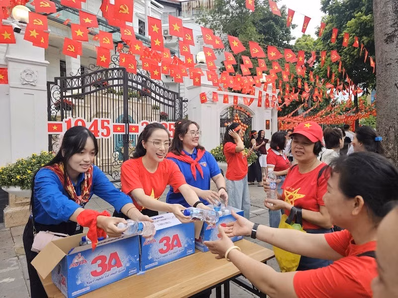 Các bạn tình nguyện viên phát nước cho người dân đi xem sơ duyệt diễu binh, diễu hành tại Hà Nội. (Ảnh: THẾ ĐẠI)