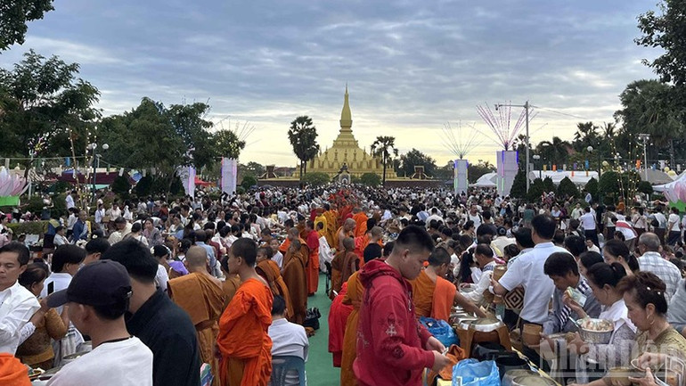 Người dân và du khách tham gia nghi lễ cúng dường tại khu vực That Luang. (Ảnh: DUY TOÀN) ndo_br_2.jpg