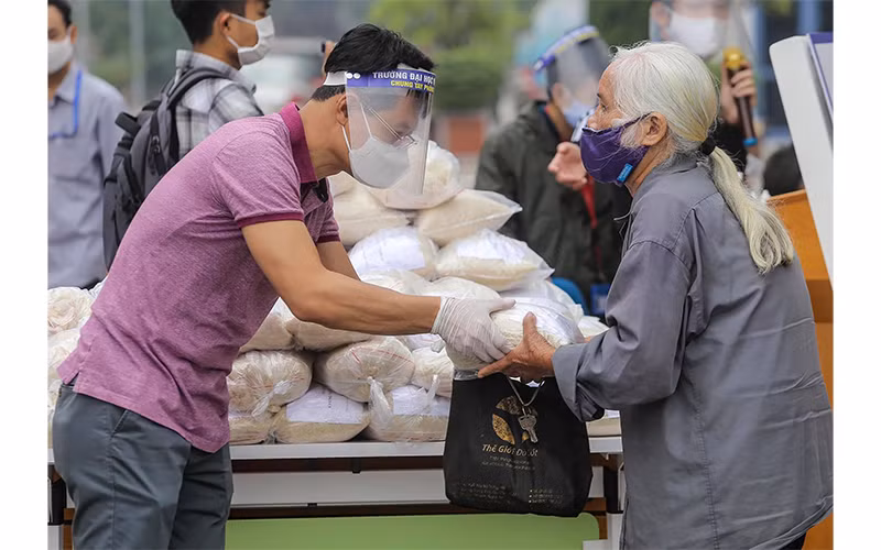 Tình nguyện viên phát gạo cho người nghèo bị ảnh hưởng do dịch Covid-19 tại quận Hai Bà Trưng (Hà Nội). Ảnh: CTV