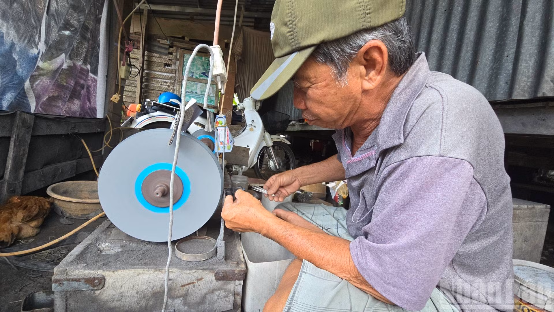 Ông Nguyễn Tấn Đức ngồi mài lưỡi câu.