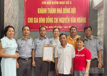 Đồng chí Vũ Văn Tài, Bí thư Đảng ủy Chi đội Kiểm ngư số 3 (thứ hai từ trái sang) trao kinh phí hỗ trợ nhà đồng đội cho gia đình đồng chí Nguyễn Văn Hoàng. (Ảnh: TIẾN DŨNG)