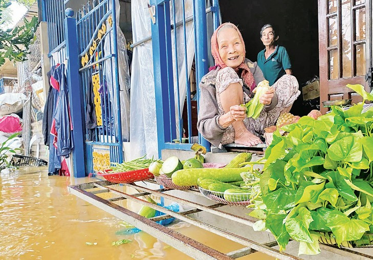 Bà cụ bán rau trên nước lũ ở bên cửa Hữu Kinh thành Huế cùng nụ cười rất Huế. (Ảnh DƯƠNG QUANG TIẾN) s2.jpg