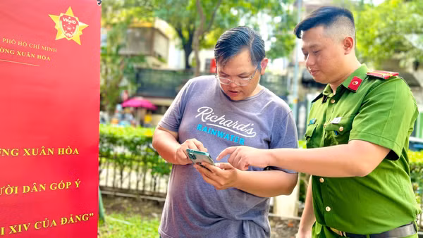 Công an phường Xuân Hòa hướng dẫn người dân thao tác các tiện ích trên ứng dụng VNeID. (Ảnh: QUANG QUÝ)