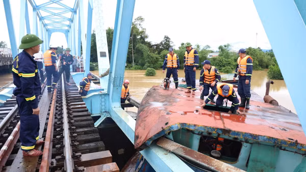 Lực lượng chức năng tiến hành cắt phần mái sà lan bị mắc kẹt với cầu đường sắt. (Ảnh: Công an tỉnh Quảng Trị)