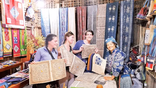 Du khách nước ngoài chọn sản phẩm vải lanh vẽ sáp ong tại Hợp tác xã dệt lanh Lùng Tám.