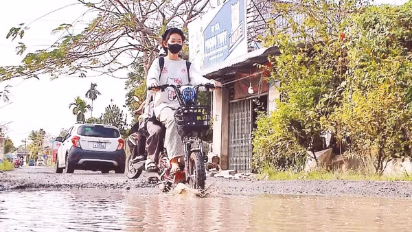 Học sinh đến trường qua đoạn Đường tỉnh 923 hư hỏng, ngập nước tại xã Phong Điền.