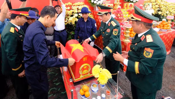 Các đại biểu thực hiện nghi lễ phủ cờ Tổ quốc lên hài cốt liệt sĩ vừa quy tập tại xã Minh Đức, thành phố Đồng Nai.