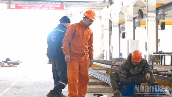 Anh Trần Văn Sơn (áo cam) trong xưởng làm việc. (Ảnh: THANH THỂ)