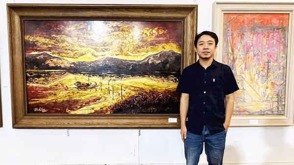 Họa sĩ Nguyễn Bỉnh Sơn bên tác phẩm của mình.