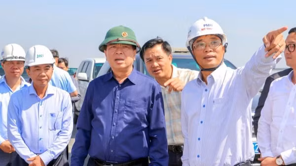 Lãnh đạo Ban Quản lý dự án Mỹ Thuận báo cáo tiến độ dự án cùng với Bộ trưởng Xây dựng Trần Hồng Minh (áo xanh đậm) tại hiện trường.