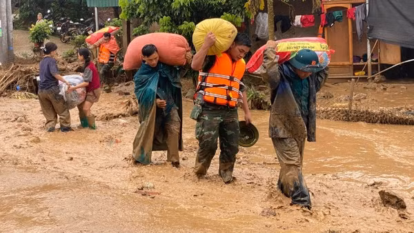 Lực lượng cứu hộ di chuyển tài sản giúp người dân vùng lũ đến nơi an toàn.