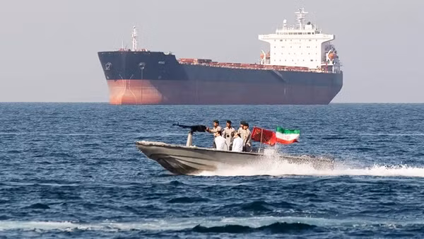 Xuồng vũ trang của Iran hoạt động gần một tàu hàng ở Eo biển Hormuz. Ảnh: AP