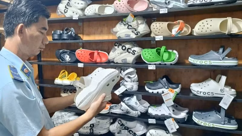 Lực lượng Quản lý thị trường Thành phố Hồ Chí Minh kiểm tra dép có dấu hiệu giả mạo nhãn hiệu tại một hộ kinh doanh.