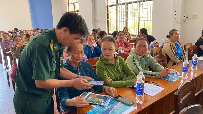 Cán bộ Đồn Biên phòng Tam Quan Nam phát tờ rơi tuyên truyền và hướng dẫn ngư dân quét mã QR.