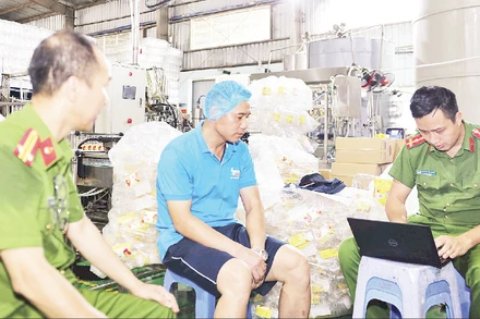 Lực lượng Công an tỉnh Hưng Yên kiểm tra, làm việc với Công ty TNHH Sản xuất và Xuất nhập khẩu Nhật Minh Food. (Ảnh TTXVN)