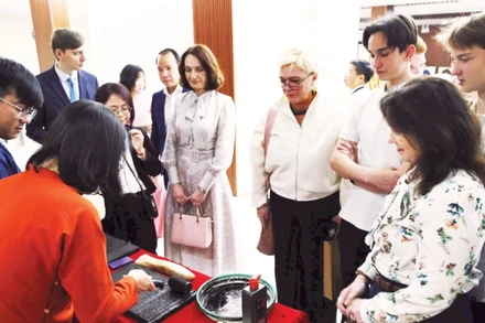 Du khách nước ngoài thích thú khi trải nghiệm in dập mộc bản.