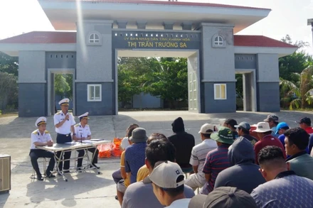 Cán bộ Trung tâm Dịch vụ hậu cần kỹ thuật Trường Sa tuyên truyền, phổ biến cho ngư dân về Chỉ thị 45 và về hoạt động của các âu tàu, làng chài trên quần đảo Trường Sa. (Ảnh: Đức Thuận)