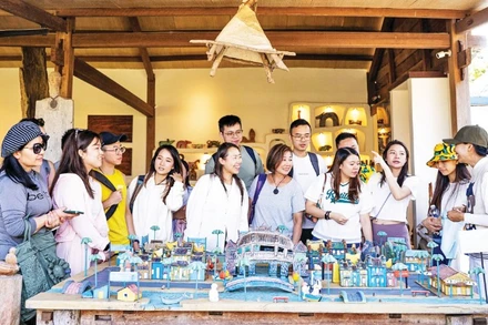 Du khách tìm hiểu nghệ thuật điêu khắc gỗ tại Làng Củi Lũ.