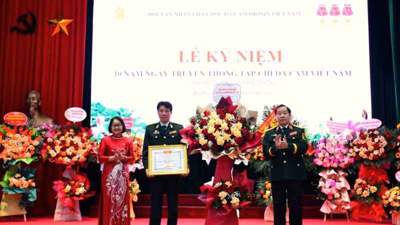 Trung tướng Nguyễn Hữu Chính tặng hoa chúc mừng và trao Bằng khen của Trung ương Hội Nạn nhân chất độc da cam/dioxin Việt Nam cho Tạp chí Da cam Việt Nam. 