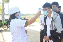 Thí sinh Trường THPT Hùng Vương (huyện Thăng Bình) được kiểm tra nhiệt độ khi đến làm thủ tục dự thi.