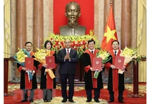 Chủ tịch nước Nguyễn Xuân Phúc trao quyết định và tặng hoa chúc mừng 4 thẩm phán Tòa án Nhân dân tối cao. (Ảnh: TTXVN) 