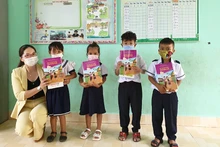 Cô Doãn Kim Huế, Hiệu trường Trường Tiểu học Cao Bá Quát trao sách giáo dục địa phương và tập vở do Báo Nhân Dân vận động cho các em học sinh. (Ảnh: Phúc Thắng)