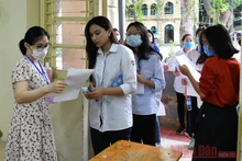 Thí sinh gỡ khẩu trang để cán bộ coi thi kiểm tra, sau đó đeo khẩu trang vào phòng thi và trong suốt thời gian làm bài thi. Ảnh: THUỶ NGUYÊN