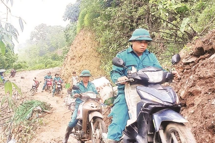 Lực lượng dân quân dùng xe máy chở gạch lên núi giúp xây nhà mới cho người dân thôn Phia Bay.
