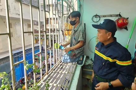 Cán bộ phòng cháy, chữa cháy giám sát việc cắt bỏ "chuồng cọp" tại một chung cư cũ trên địa bàn thành phố (Ảnh: HÀ KHÁNH)