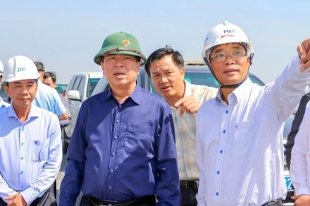 Lãnh đạo Ban Quản lý dự án Mỹ Thuận báo cáo tiến độ dự án cùng với Bộ trưởng Xây dựng Trần Hồng Minh (áo xanh đậm) tại hiện trường.
