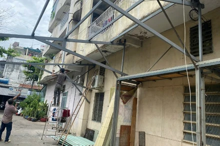 Công nhân tháo gỡ các khung sắt cơi nới tại cư xá Độc Lập sau vụ cháy. 