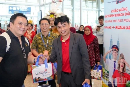 Ông Trần Hoàng Linh (phải), Giám đốc Văn phòng miền trung Vietjet đại diện hãng chào đón và tặng quà hành khách trên chuyến bay khai trương.