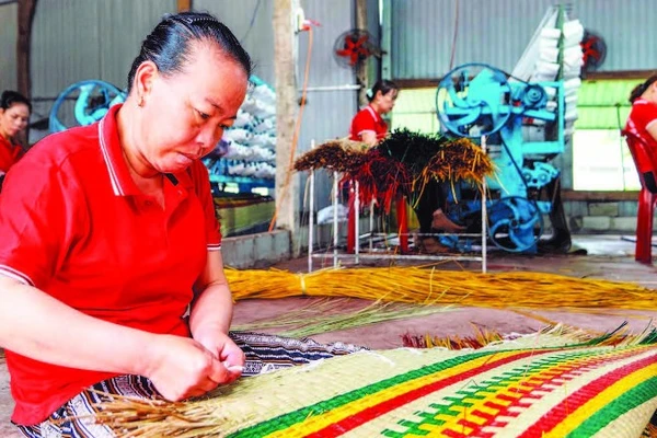 Công nhân Hợp tác xã chiếu cói Hoài Châu Bắc hoàn thiện một công đoạn làm ra chiếc chiếu thành phẩm. (Ảnh MỸ HÀ)