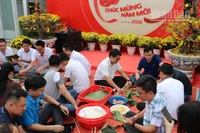 Đông đảo cán bộ, nhân viên người Việt và người Campuchia của Công ty Metfone tham gia hoạt động cùng nhau gói bánh chưng ngày Tết. (Ảnh: HUY VŨ)