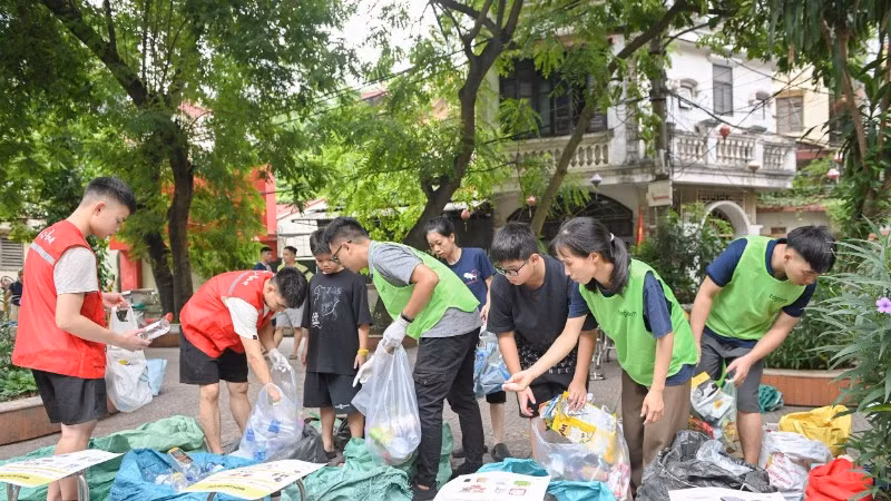 Các thành viên Tagom hướng dẫn người dân cách phân loại rác. (Ảnh THẾ ĐẠI)