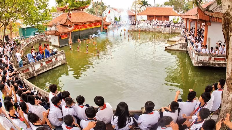 Các em học sinh xem trình diễn rối nước ở làng Thư Lâm, thành phố Hà Nội. (Ảnh: Báo Nhân Dân)