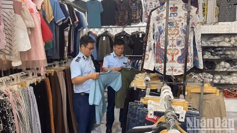 Kiểm tra hàng hóa tại cửa hàng kinh doanh quần áo may sẵn. (Ảnh: THANH SƠN)