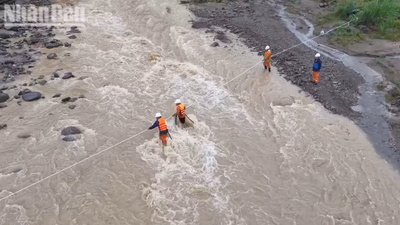 Cán bộ nhân viên Điện lực khu vực Mường La giăng dây vượt suối đến khu vực xảy ra sự cố về điện tại bản Hua Nặm, xã Mường La để khôi phục việc cấp điện.