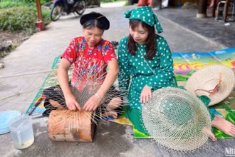 Bà Hoàng Thị Huệ (bên trái) trò chuyện và hướng dẫn khách làm nón.