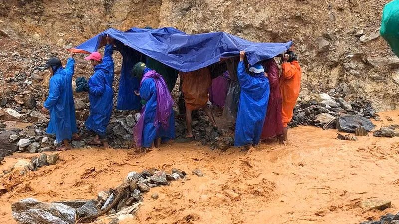 Lực lượng dân quân thường trực xã Trà Leng cùng người nhà dùng võng để khiêng bệnh nhân qua khu vực sạt lở.
