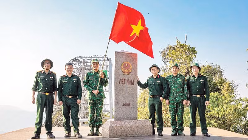Thượng úy Lục Vĩnh Lương (người cầm cờ) cùng tác giả và đoàn công tác tại Cột mốc số 0 - Ngã ba biên giới A Pa Chải - Cực tây Tổ quốc.