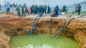 Lực lượng chức năng bơm hút nước tìm kiếm nạn nhân. (Ảnh: TUẤN SƠN)