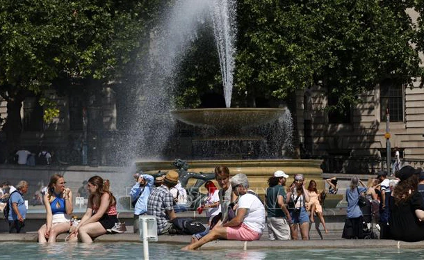 Người dân tránh nóng bên đài phun nước tại Quảng trường Trafalgar ở thủ đô London, Anh, ngày 17/6/2022. (Ảnh: AFP/TTXVN)