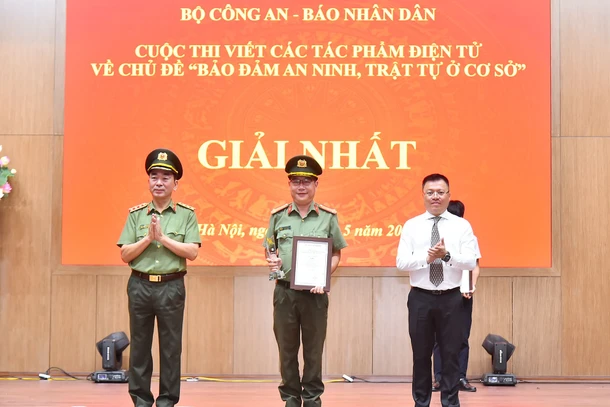 Các đồng chí Ủy viên Trung ương Đảng: Thượng tướng Trần Quốc Tỏ, Phó Bí thư Đảng ủy Công an Trung ương, Thứ trưởng điều hành hoạt động của Bộ Công an, Trưởng Ban Tổ chức cuộc thi; Lê Quốc Minh, Tổng Biên tập Báo Nhân Dân, Phó Trưởng Ban Tuyên giáo Trung ương, Chủ tịch Hội Nhà báo Việt Nam trao giải Nhất cho tác giả tại Lễ tổng kết. (Ảnh: THỦY NGUYÊN)