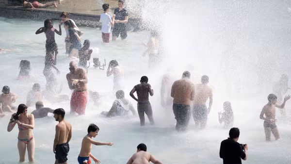 Người dân tránh nóng tại đài phun nước ở Paris, Pháp. Ảnh: THX/TTXVN